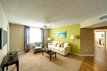 A living room with a white couch and a painting on the wall.